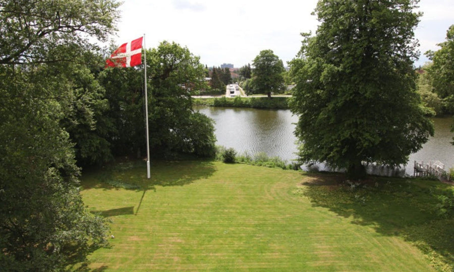 View of Bjørn Thorsen headquarters in Denmark, surrounded by green landscape and lake, reflecting long-term commitment to quality and sustainability.

