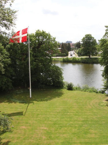 View of Bjørn Thorsen headquarters in Denmark, surrounded by green landscape and lake, reflecting long-term commitment to quality and sustainability.